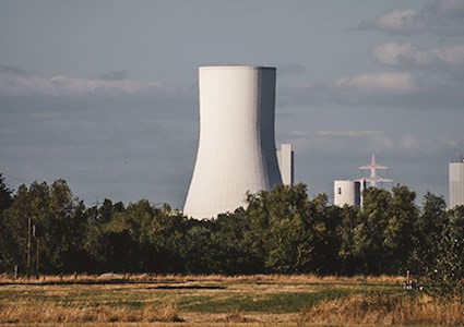 Nuclear power plant with blue sky and a field in the foreground