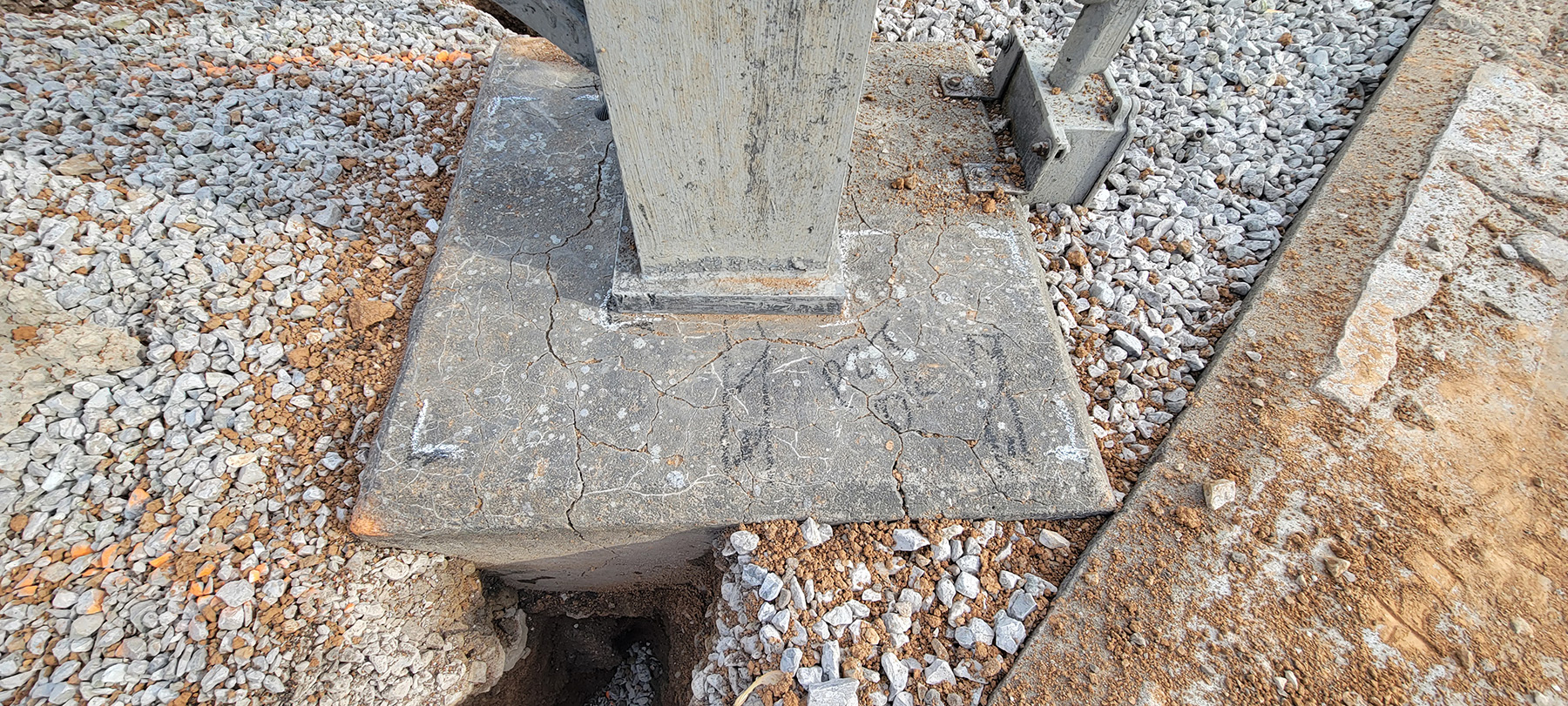 The photo shows the excavated foundation of a boxbay structure. There are cracks in the foundation. 