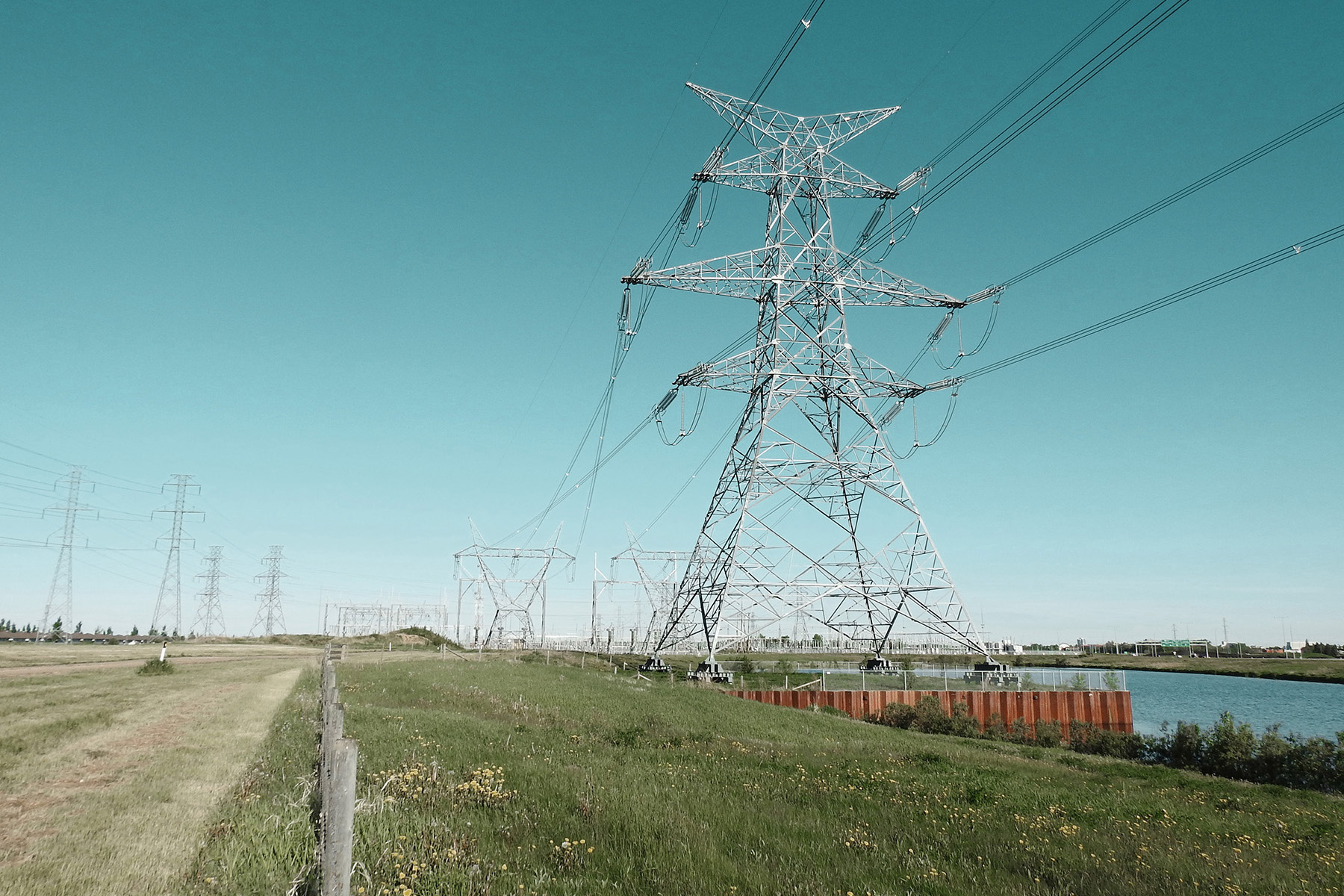 Transmission towers and wires stretch across the land, including one large prominent tower. 